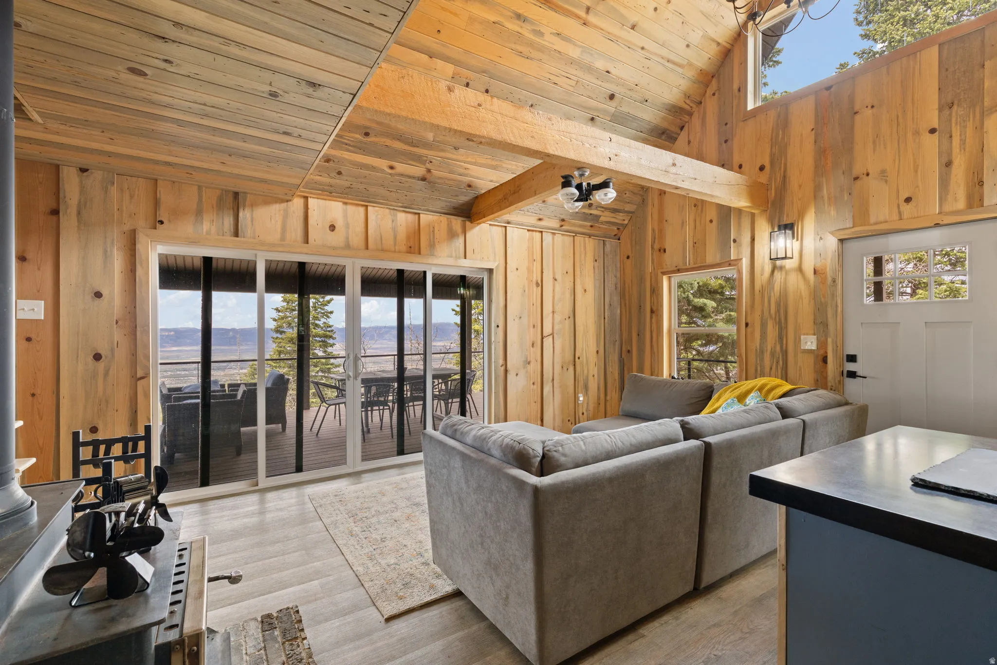 Cabin 1 - West; Living area with wooden walls, light wood finished floors, and a vaulted wood ceiling