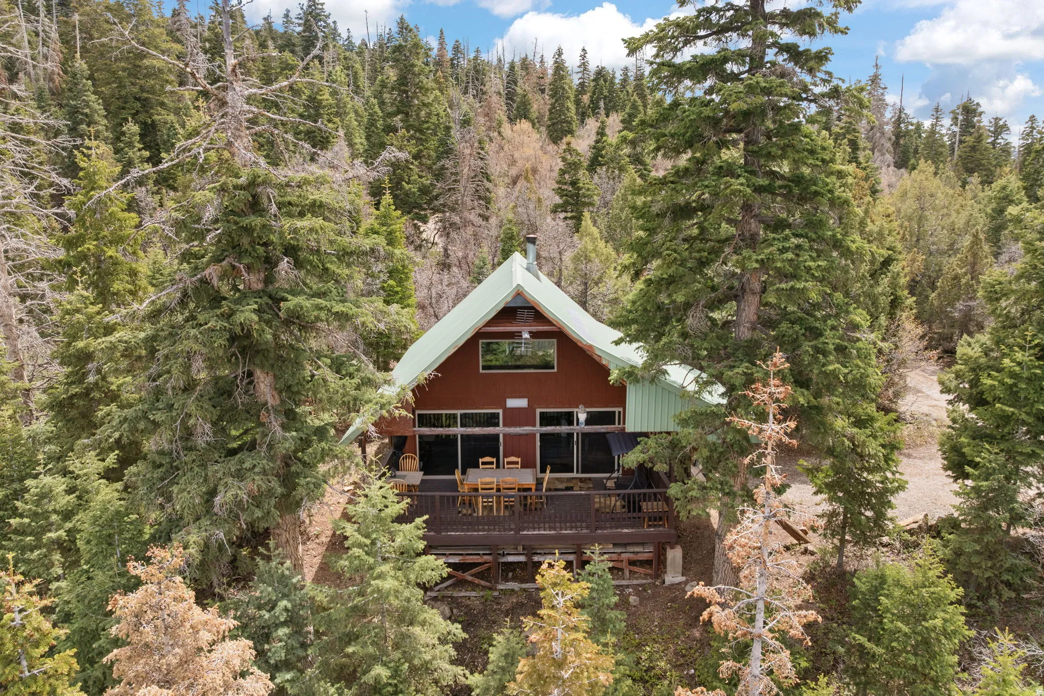 Cabin 2 - East; Back of property with a wooden deck and a view of trees