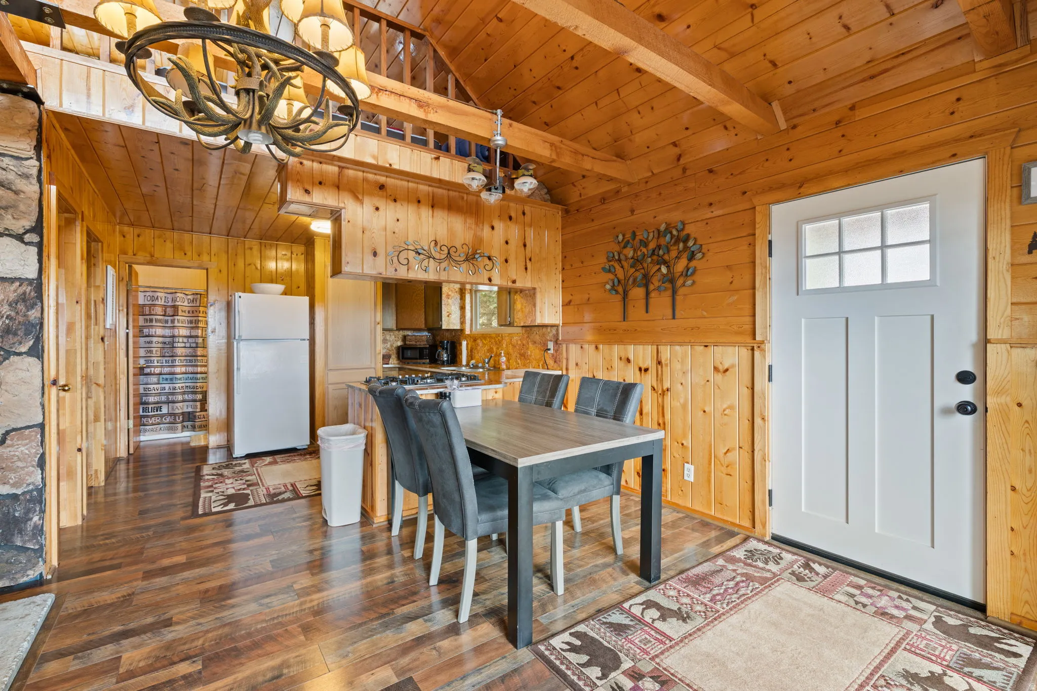 Cabin 2 - East; Dining space featuring a wooden ceiling with exposed beams, dark wood-style floors, a chandelier, and wood walls