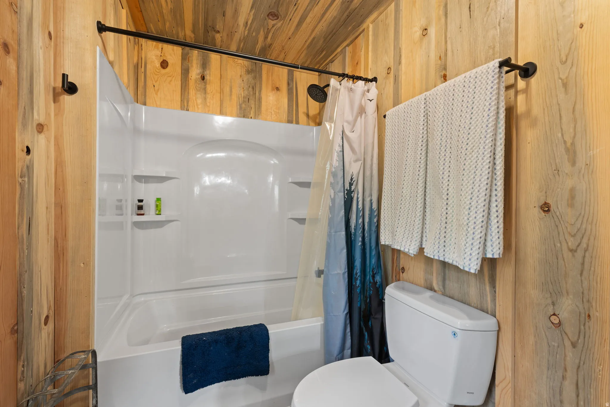 Cabin 1 - West; Full bathroom with wooden walls, shower / bath combo with shower curtain, and wooden ceiling