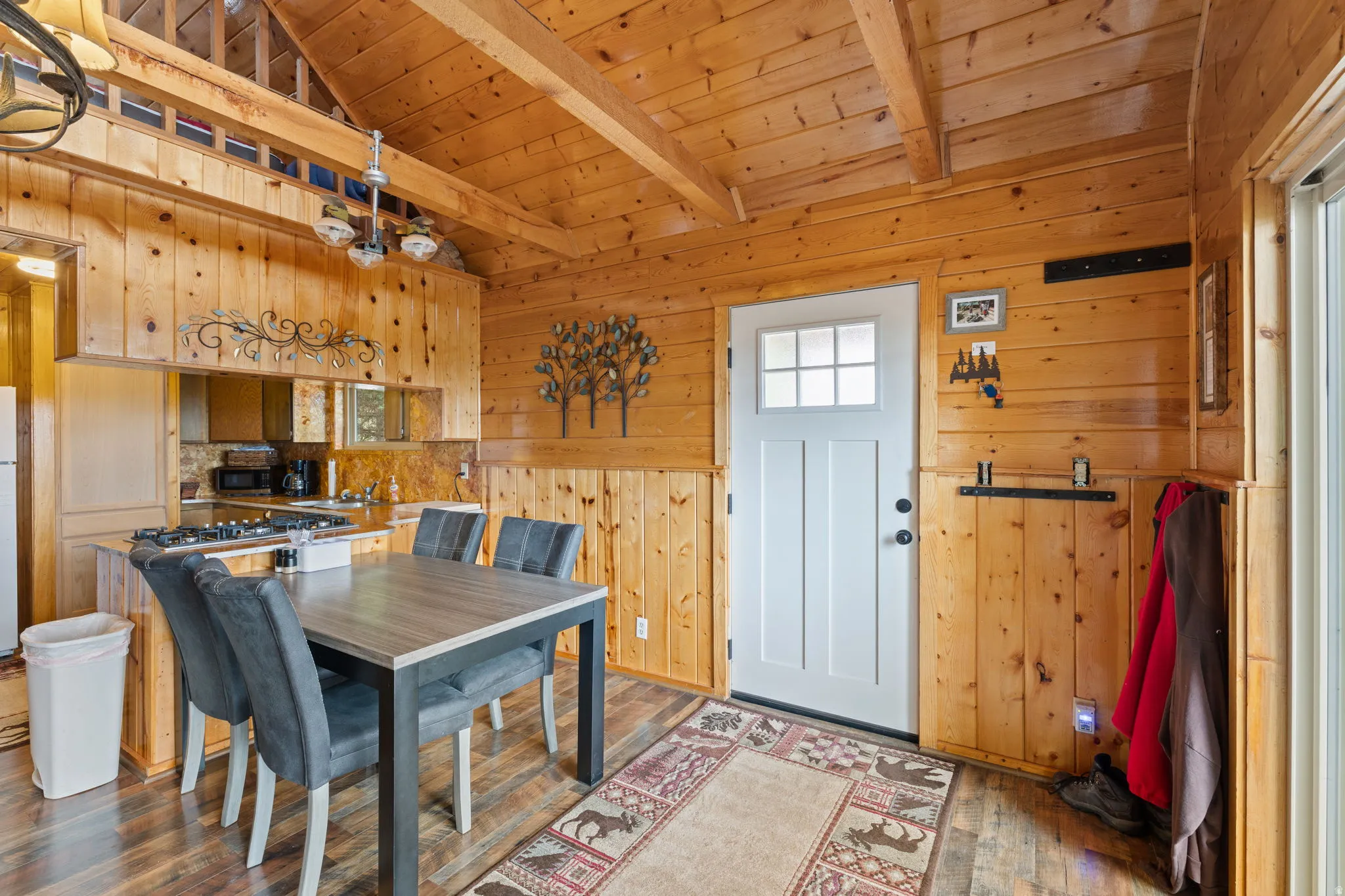 Cabin 2 - East; Dining area featuring wooden walls, hardwood / wood-style flooring, wooden ceiling, and vaulted ceiling with beams