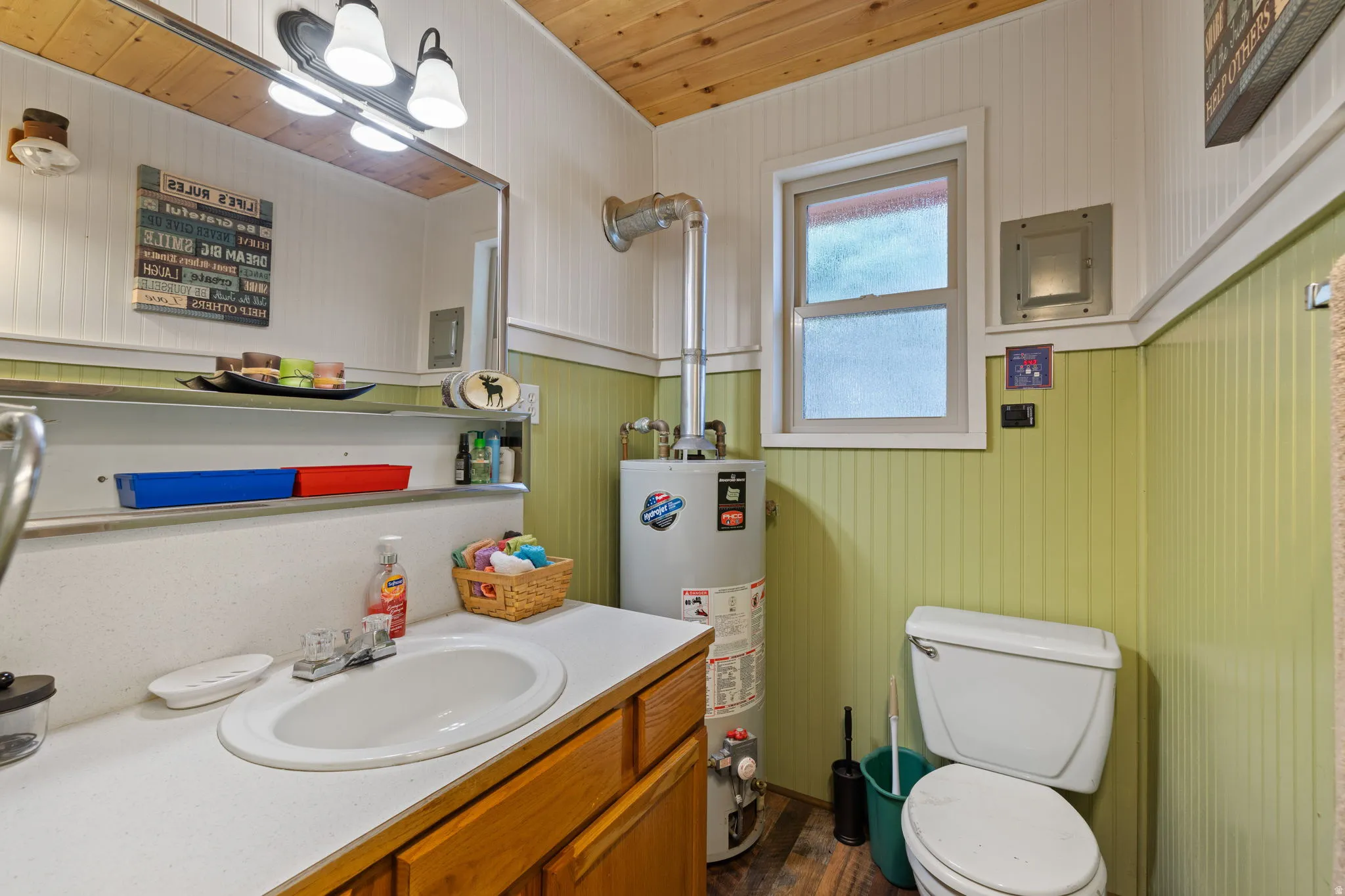 Cabin 2 - East; Bathroom featuring vanity, gas water heater, electric panel, and dark wood-style flooring