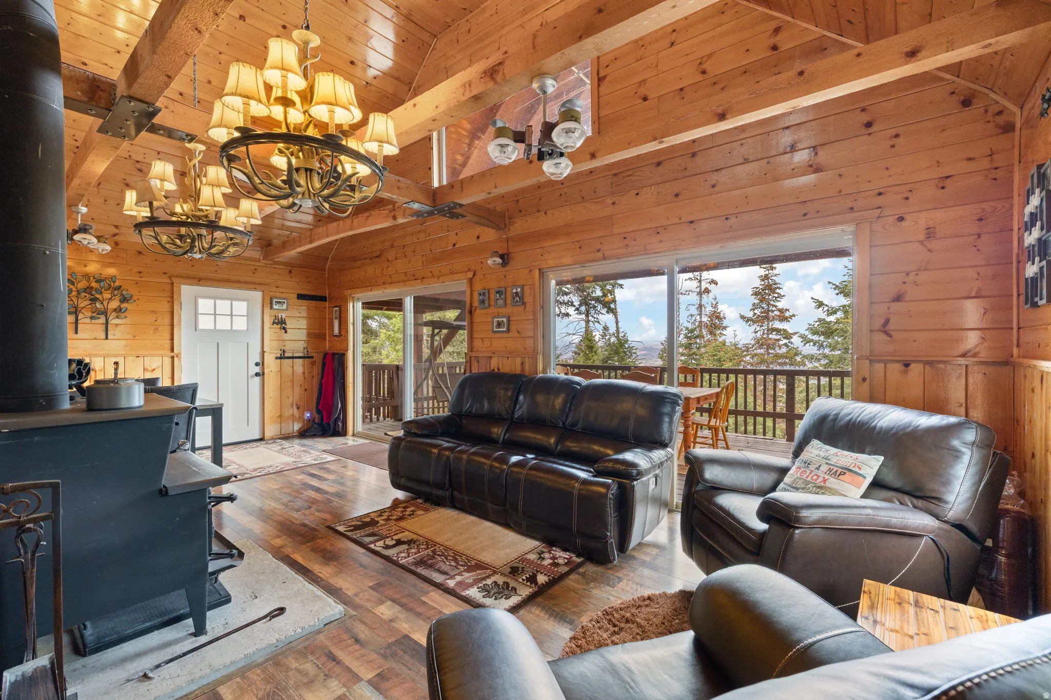 Cabin 2 - East; Living room featuring a wood stove, wood walls, wood-type flooring, hanging lights, and a high wooden beamed ceiling
