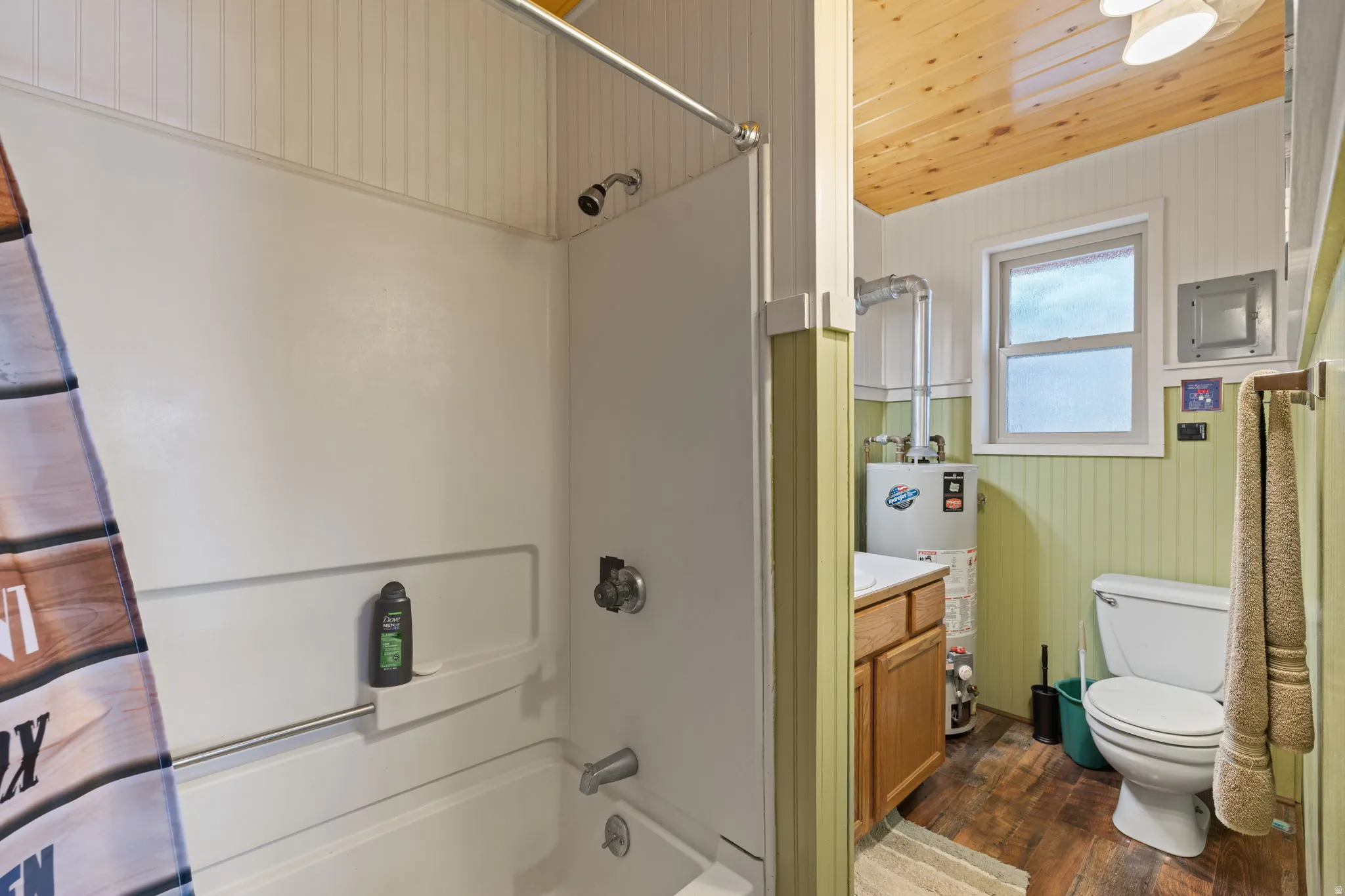 Cabin 2 - East; Bathroom featuring wooden ceiling, dark wood-type flooring, vanity, shower / bath combination with curtain, and gas water heater