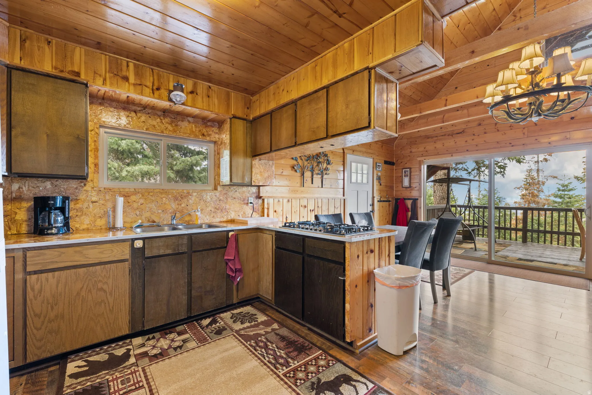 Cabin 2 - East; Kitchen featuring wood ceiling, suspended lighting, wood walls, light countertops, and dark wood-type flooring