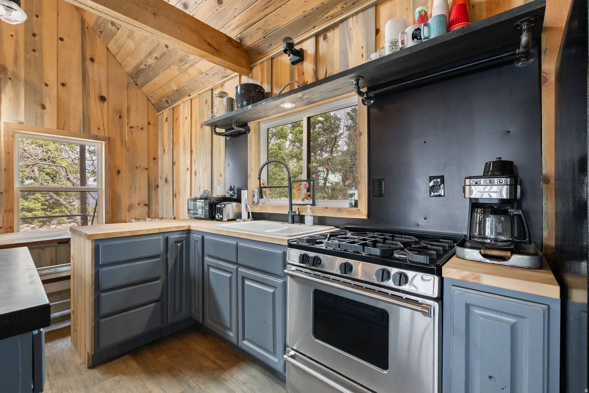 Cabin 1 - West; Kitchen with gas range, vaulted ceiling with beams, dark wood-style floors, wood counters, and wooden ceiling