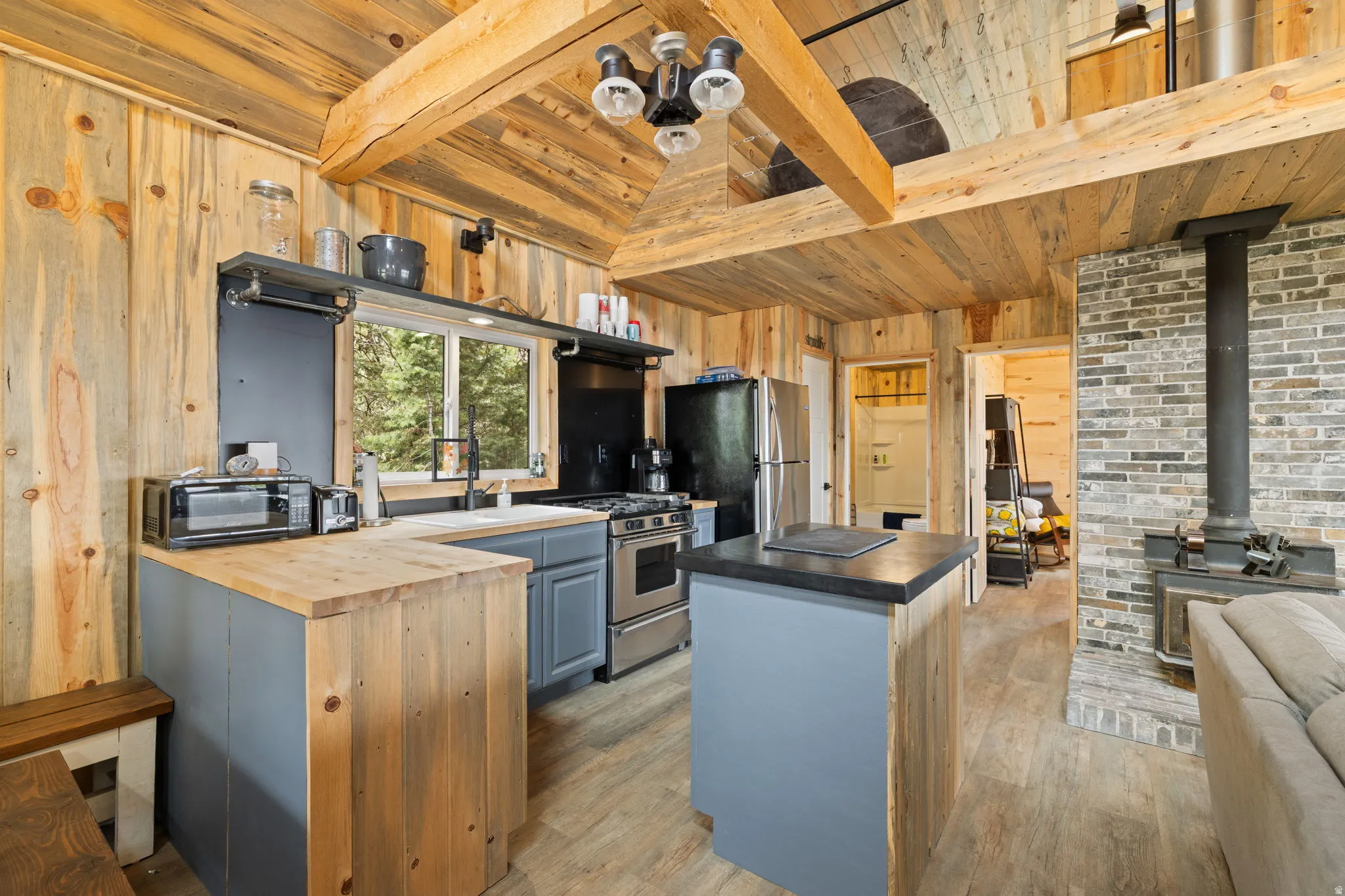 Cabin 1 - West; Kitchen featuring a kitchen island, butcher block counters, stainless steel appliances, wooden walls, and light wood-style flooring