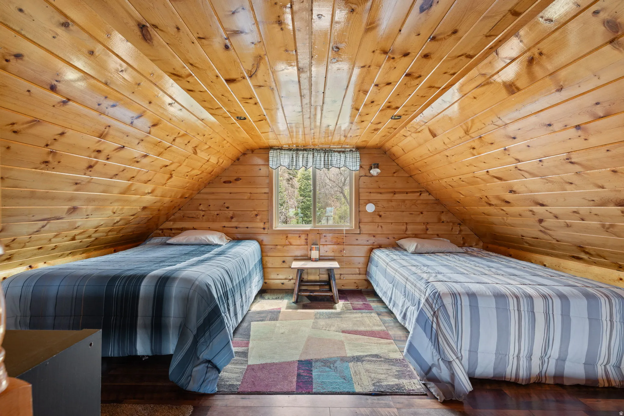 Cabin 2 - East; Loft/Bedroom featuring a vaulted wooden ceiling, wood walls, and hardwood / wood-style flooring