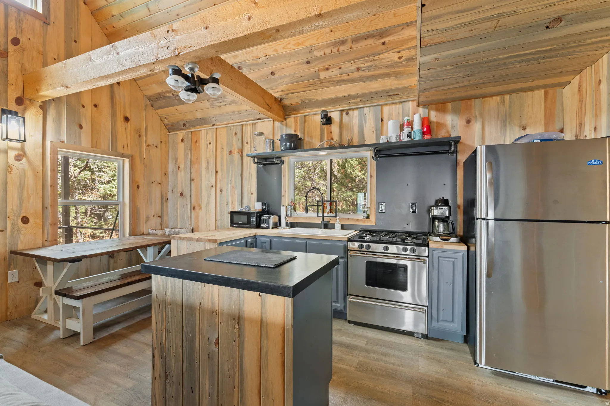Cabin 1 - West; Kitchen with stainless steel appliances, plenty of natural light, lofted ceiling with beams, a center island, and light wood finished floors