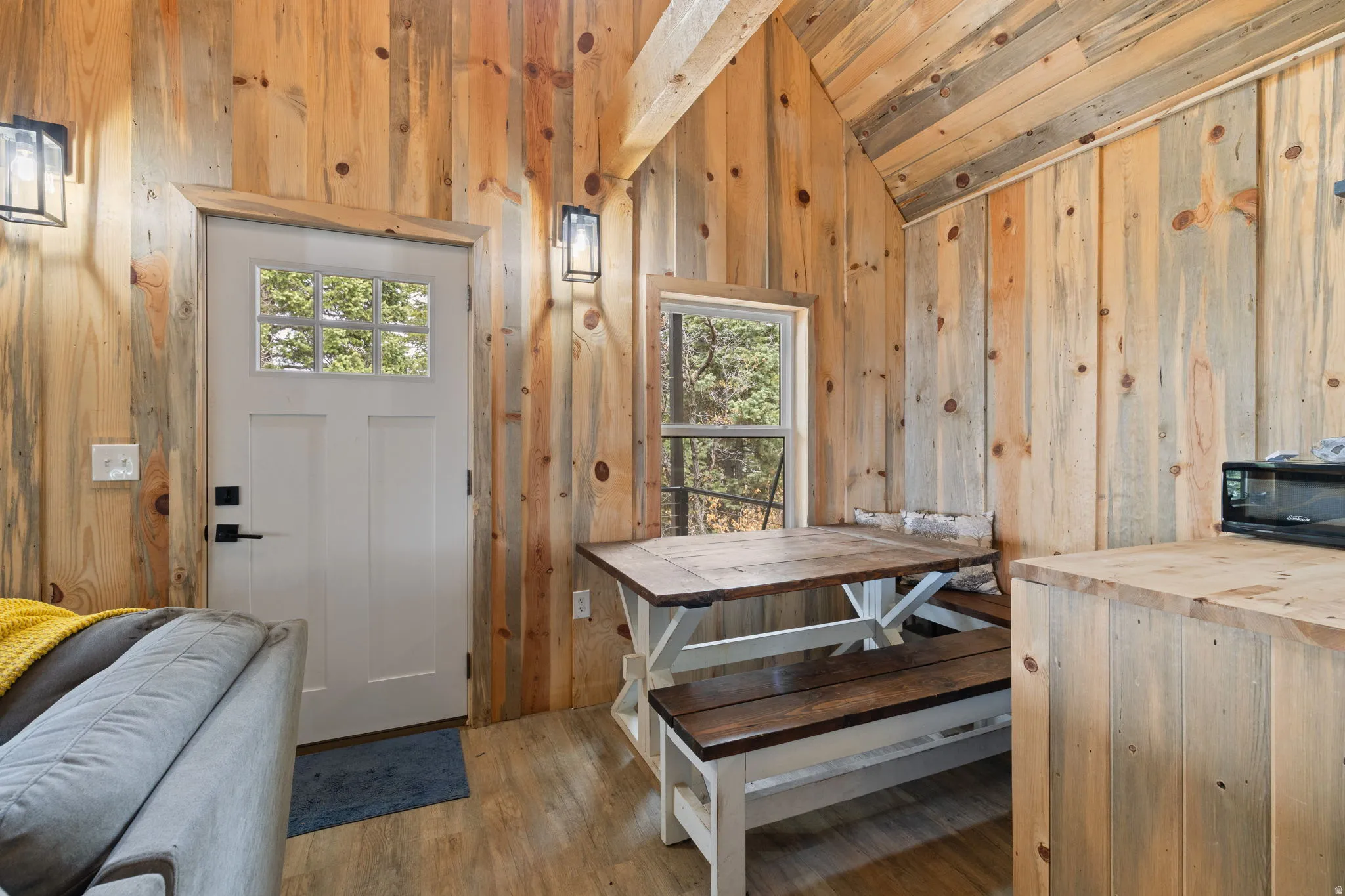 Cabin 1 - West; Dining space with light wood-style floors, lofted ceiling, and wood walls