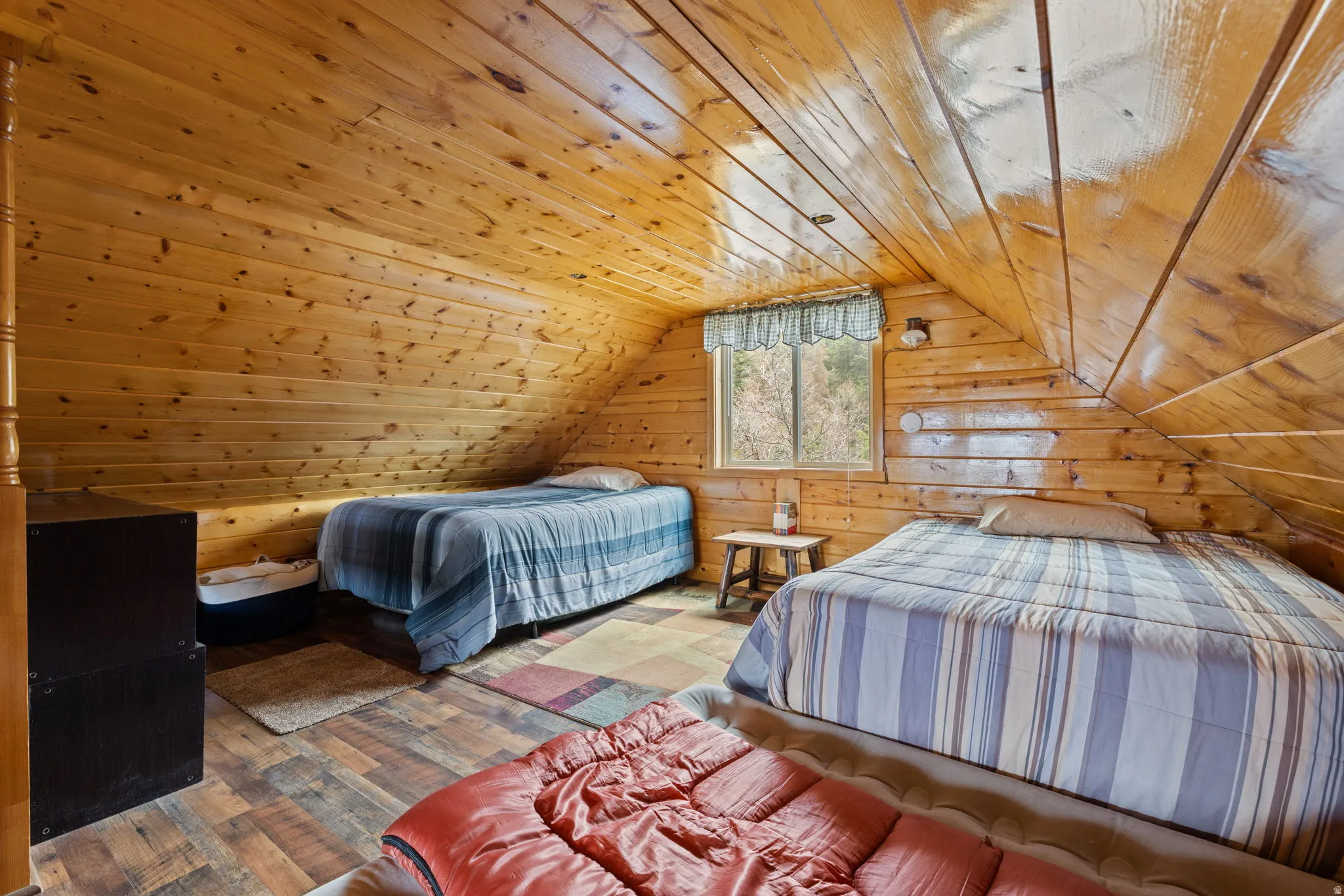 Cabin 2 - East; Loft/Bedroom featuring wood walls, a vaulted wood ceiling, and hardwood / wood-style flooring