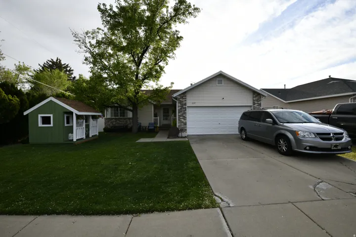 Ranch-style house with concrete driveway, a garage, a front yard, an outbuilding, and brick siding