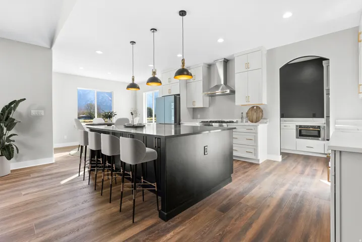 Kitchen with a kitchen island, a breakfast bar area, dual tone cabinets, dark wood-style floors, and freestanding refrigerator
