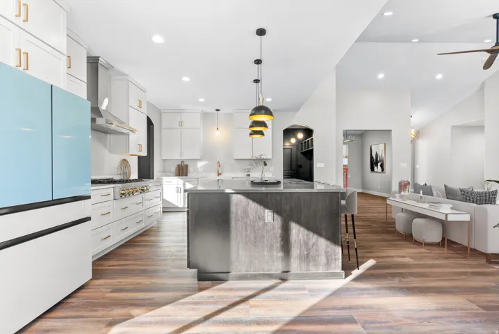 Dual tone kitchen with fridge, dark wood-style floors, a kitchen bar, open floor plan, and pendant lighting