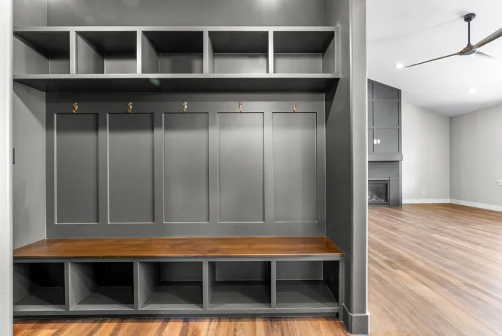 Mudroom featuring light wood-style floors, a large fireplace, ceiling fan, and vaulted ceiling