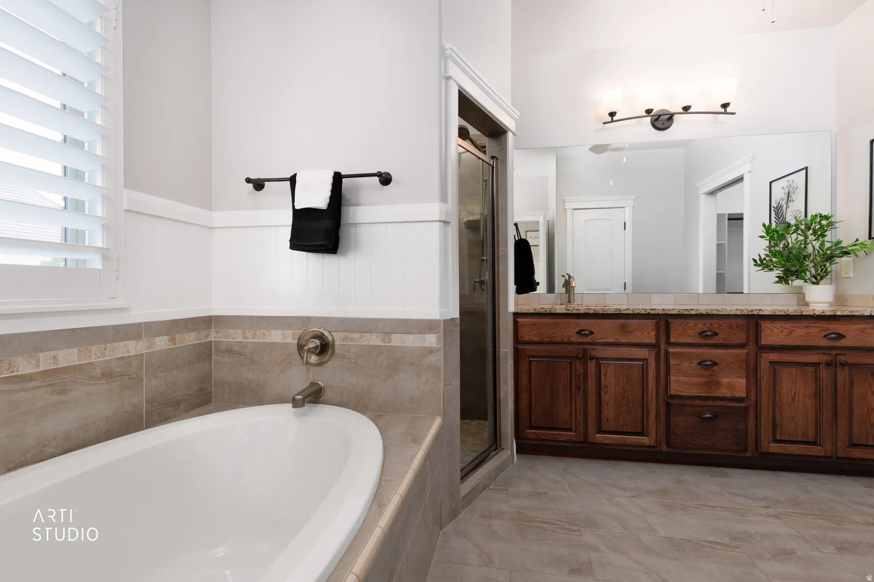 Bathroom with double vanity, a bath, a shower stall, and wainscoting