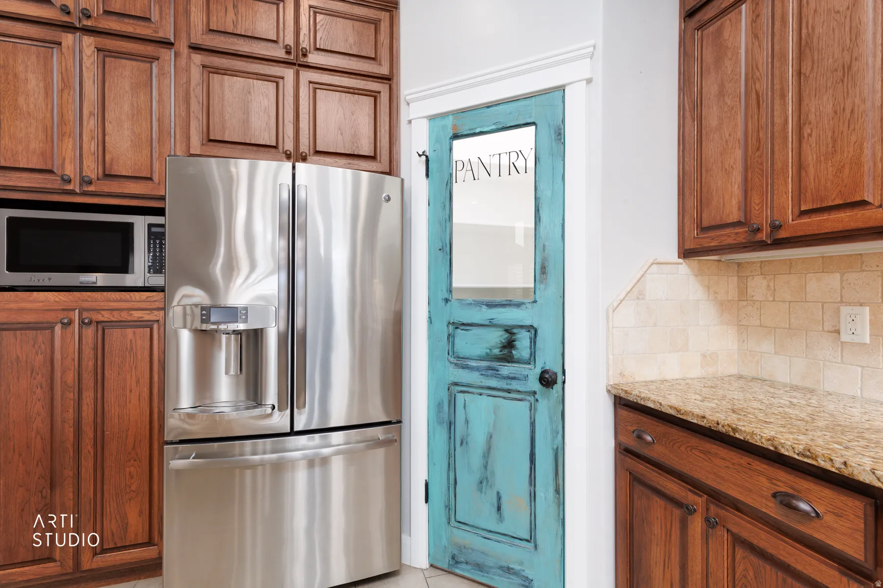Kitchen featuring stainless steel appliances, decorative backsplash, wood finish cabinetry, and light stone countertops