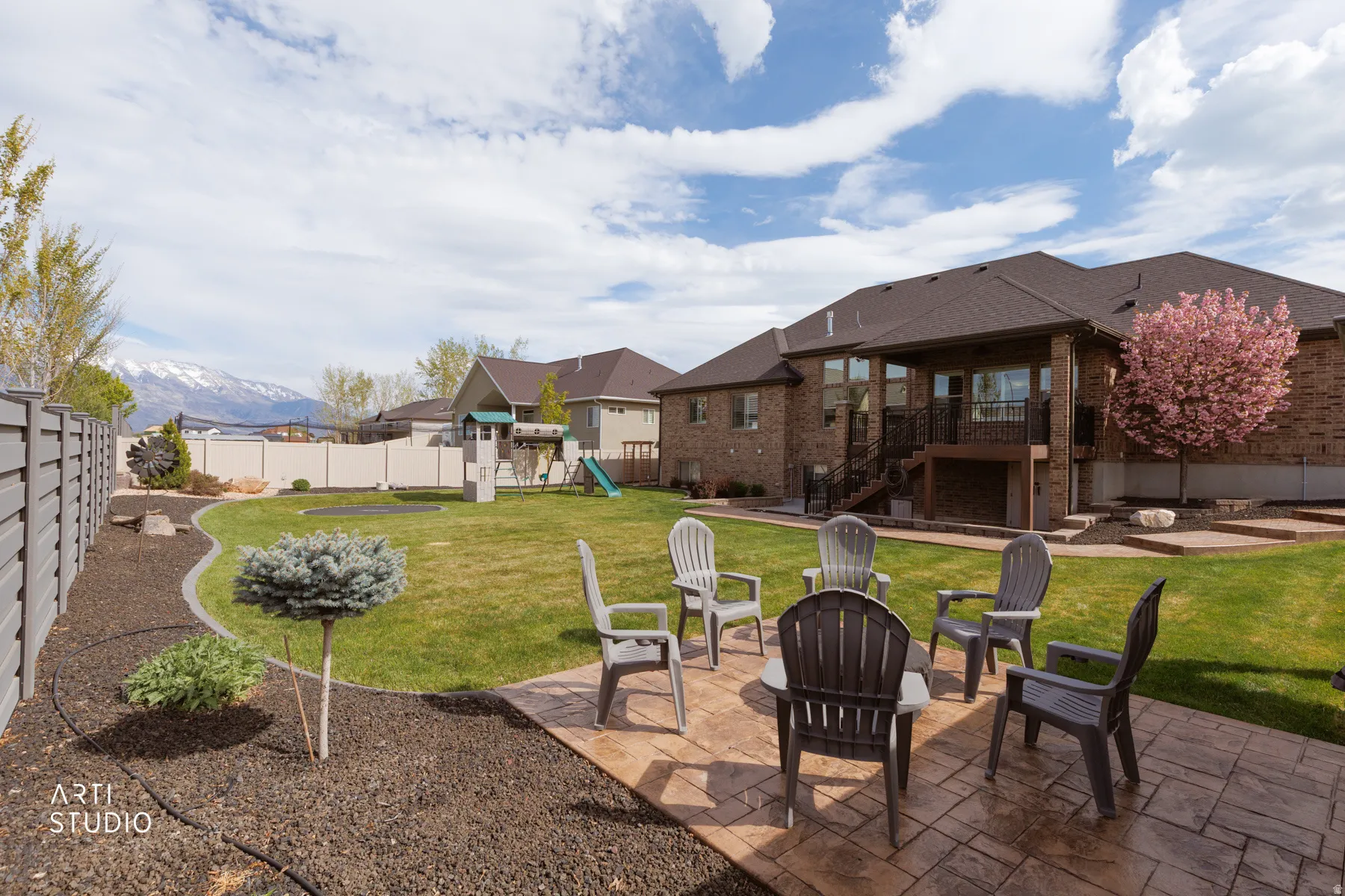 Fenced backyard featuring a patio area, an outdoor fire pit, a playground, a balcony, and a mountain view
