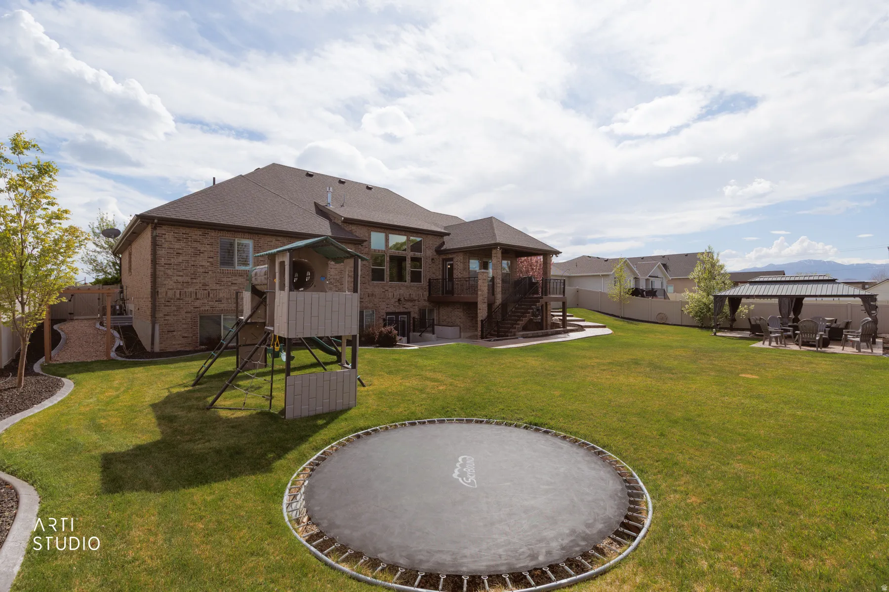 Back of property with a patio area, a playground, brick siding, a fenced backyard, and a balcony