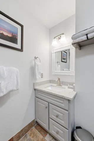 Bathroom featuring a textured wall, vanity, and stone tile floors