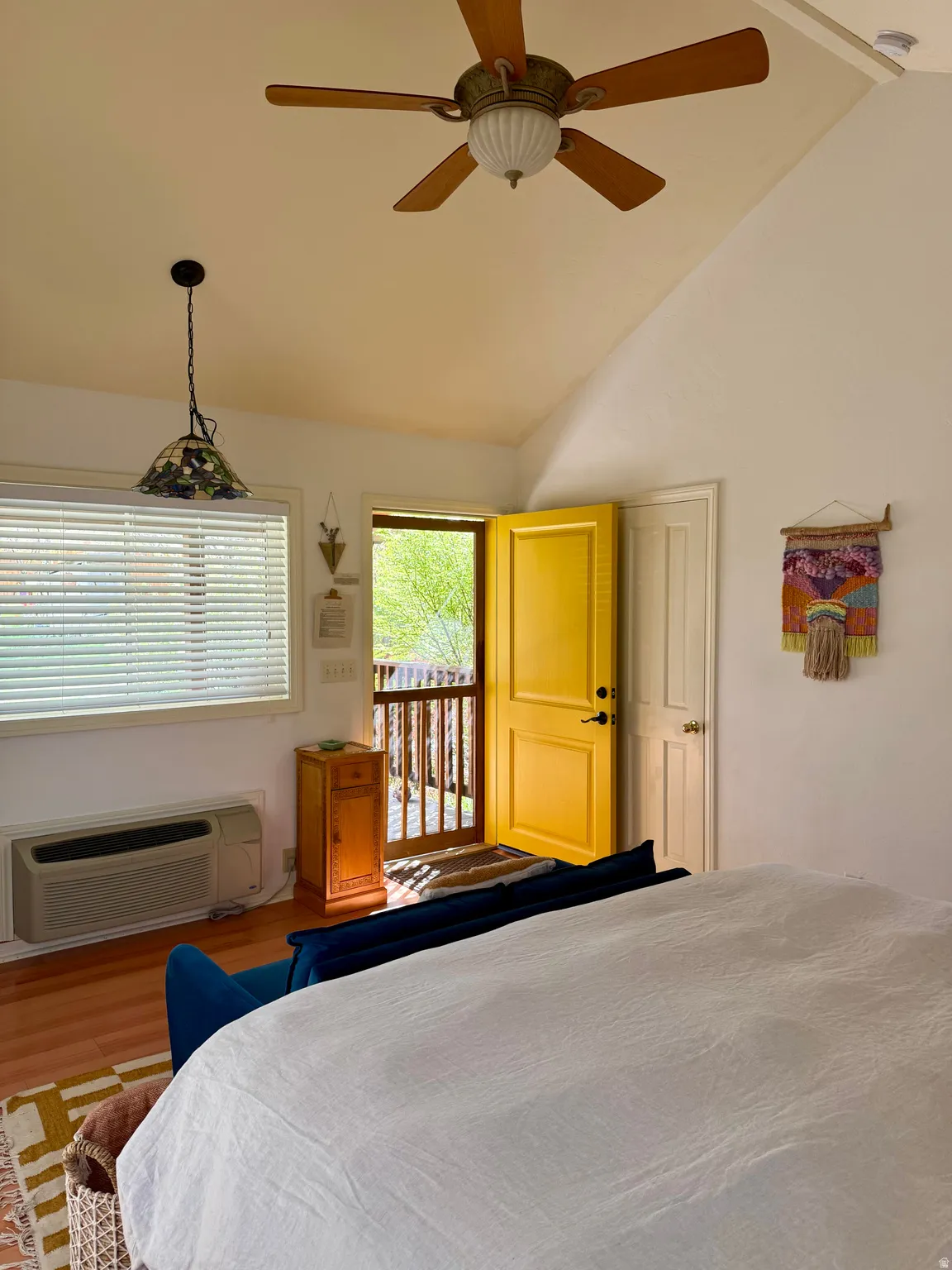 Bedroom featuring vaulted ceiling, wood finished floors, access to exterior, and a ceiling fan