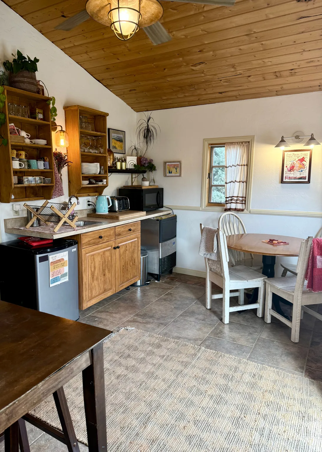 Kitchen with a vaulted wood ceiling, wood finish cabinetry, fridge, black microwave, and light countertops