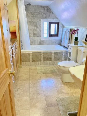 Full bathroom featuring tiled shower / bath, lofted ceiling, vanity, and light tile patterned floors