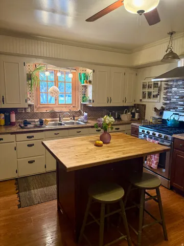 Kitchen featuring decorative backsplash, a kitchen breakfast bar, stainless steel gas range oven, wood counters, and a center island