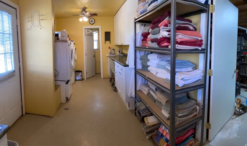 Kitchen with white cabinetry, dark countertops, a ceiling fan, and finished concrete flooring