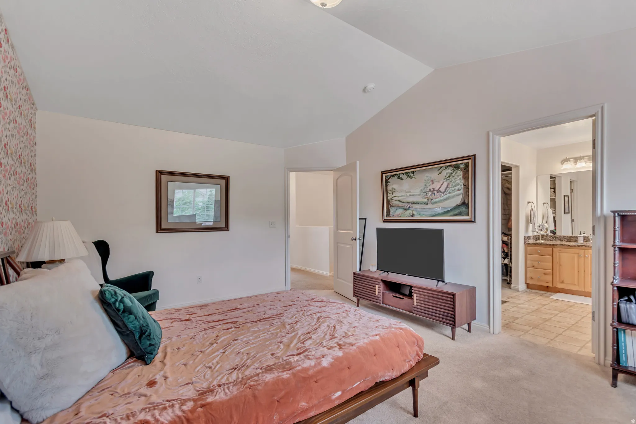 Bedroom featuring vaulted ceiling, light carpet, and connected bathroom