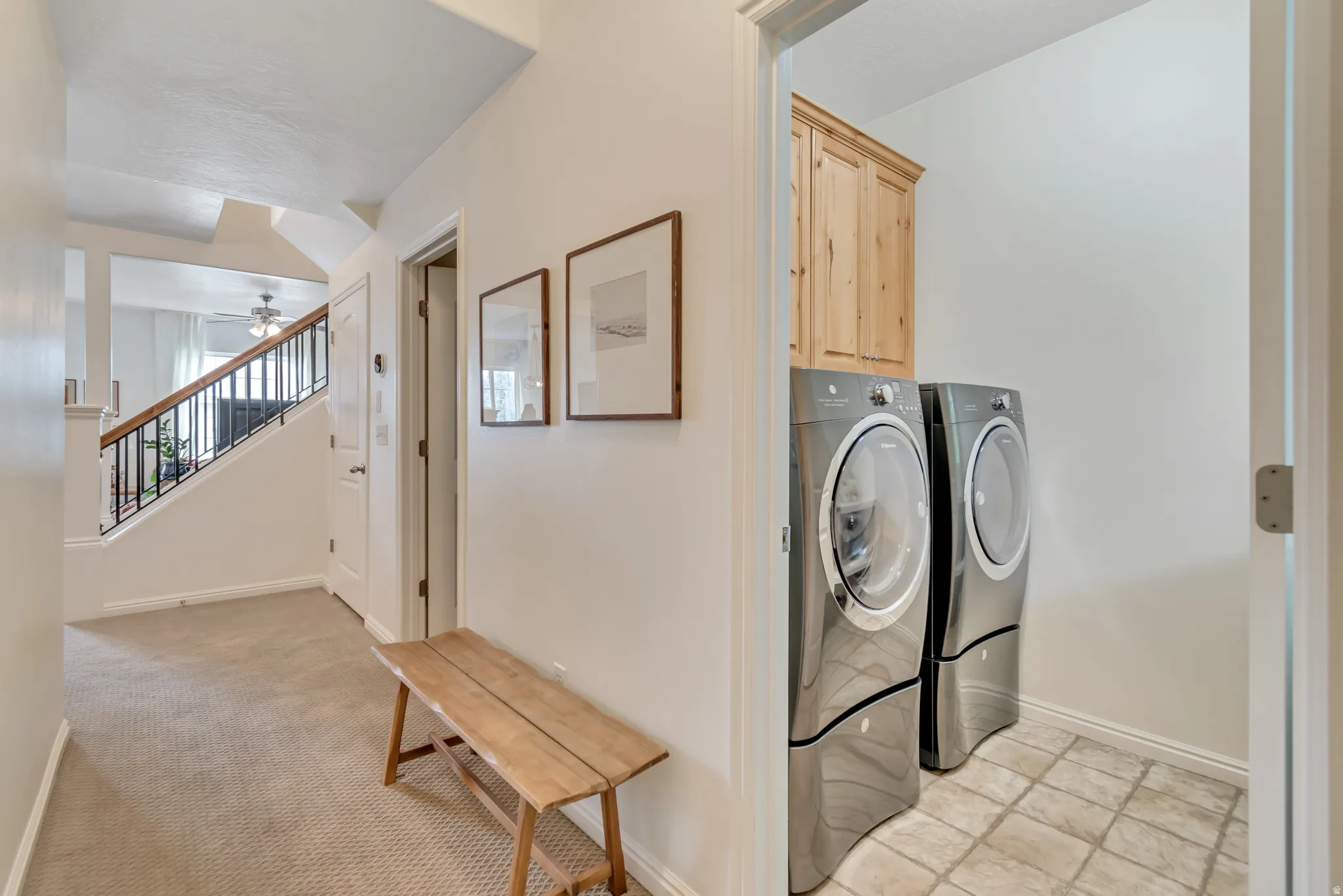 Laundry room featuring cabinet space, light carpet, ceiling fan, and washing machine and clothes dryer that are included in purchase.