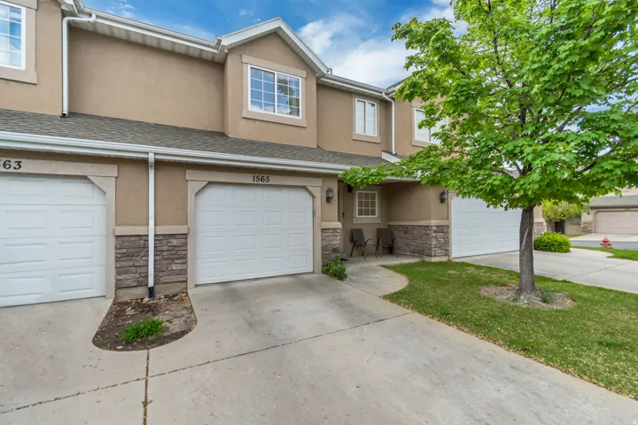 Traditional-style home with stone, stucco siding, driveway, and an attached garage