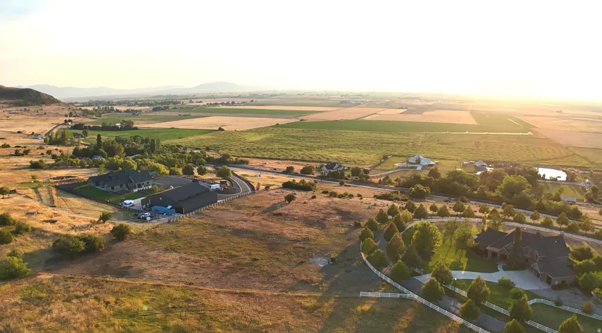 Aerial view of sparsely populated area with abundant farmland and a mountainous background
