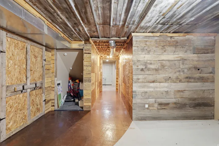 Hall with concrete flooring, wooden walls, and wooden ceiling