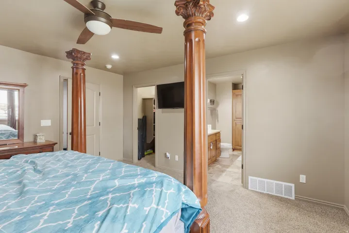 Bedroom featuring light colored carpet, a spacious closet, recessed lighting, ceiling fan, and connected bathroom