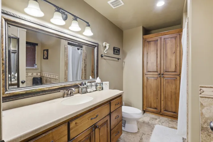 Bathroom featuring vanity, curtained shower, a closet, and light stone finish flooring