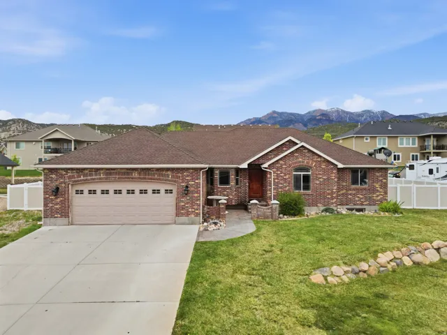 Ranch-style home with a shingled roof, a garage, driveway, brick siding, and a mountain view