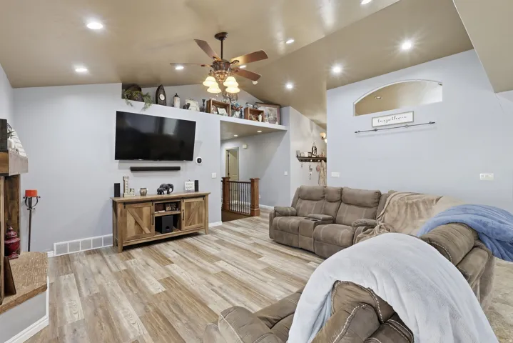 Living area with light wood-style flooring, ceiling fan, lofted ceiling, and recessed lighting