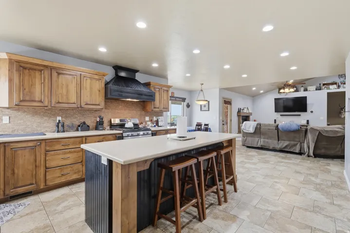 Kitchen with open floor plan, a breakfast bar, light countertops, wood finish cabinetry, and a center island