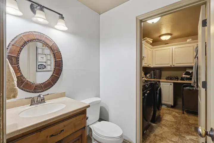 Bathroom featuring vanity, washer and clothes dryer, and light stone finish flooring