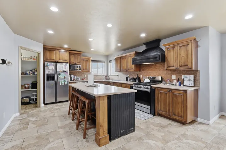 Kitchen featuring wood finish cabinets, stainless steel appliances, a kitchen bar, a center island, and recessed lighting