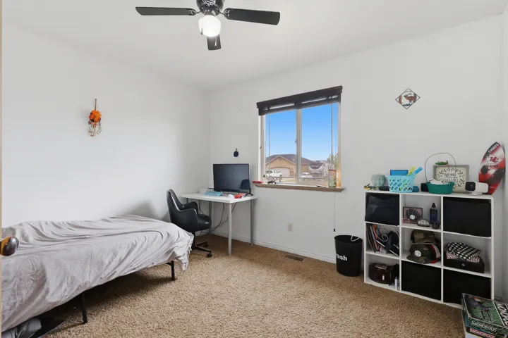 Bedroom featuring light carpet, ceiling fan, and an office area