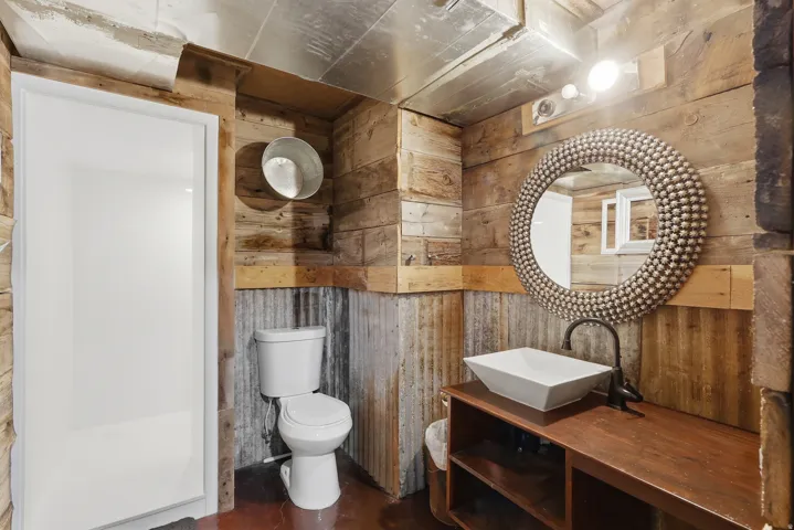 Full bathroom with wooden walls, vanity, and concrete flooring
