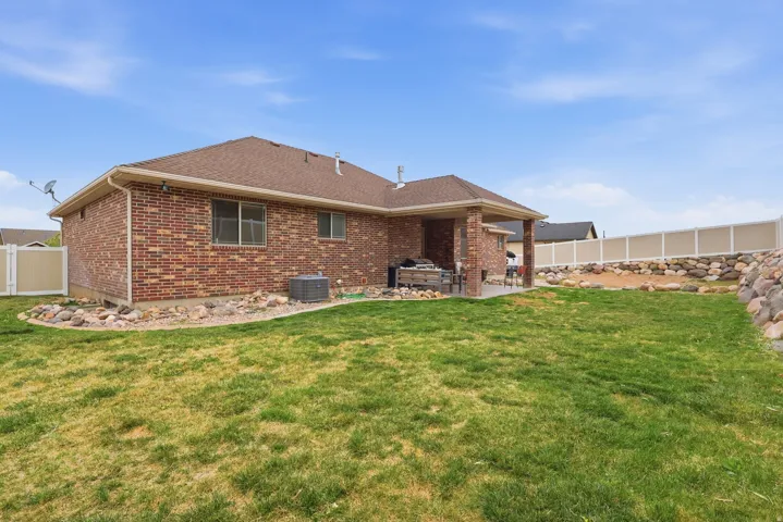Rear view of house with a fenced backyard, brick siding, a patio, and roof with shingles