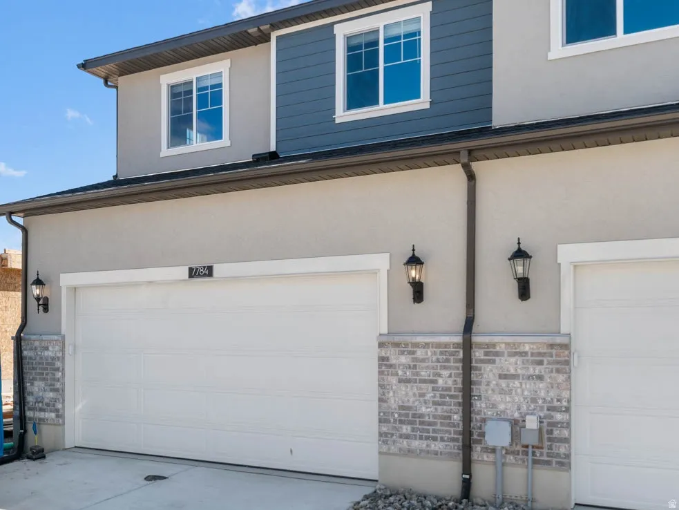 View of front of home featuring stucco siding, driveway, an attached garage, and stone siding