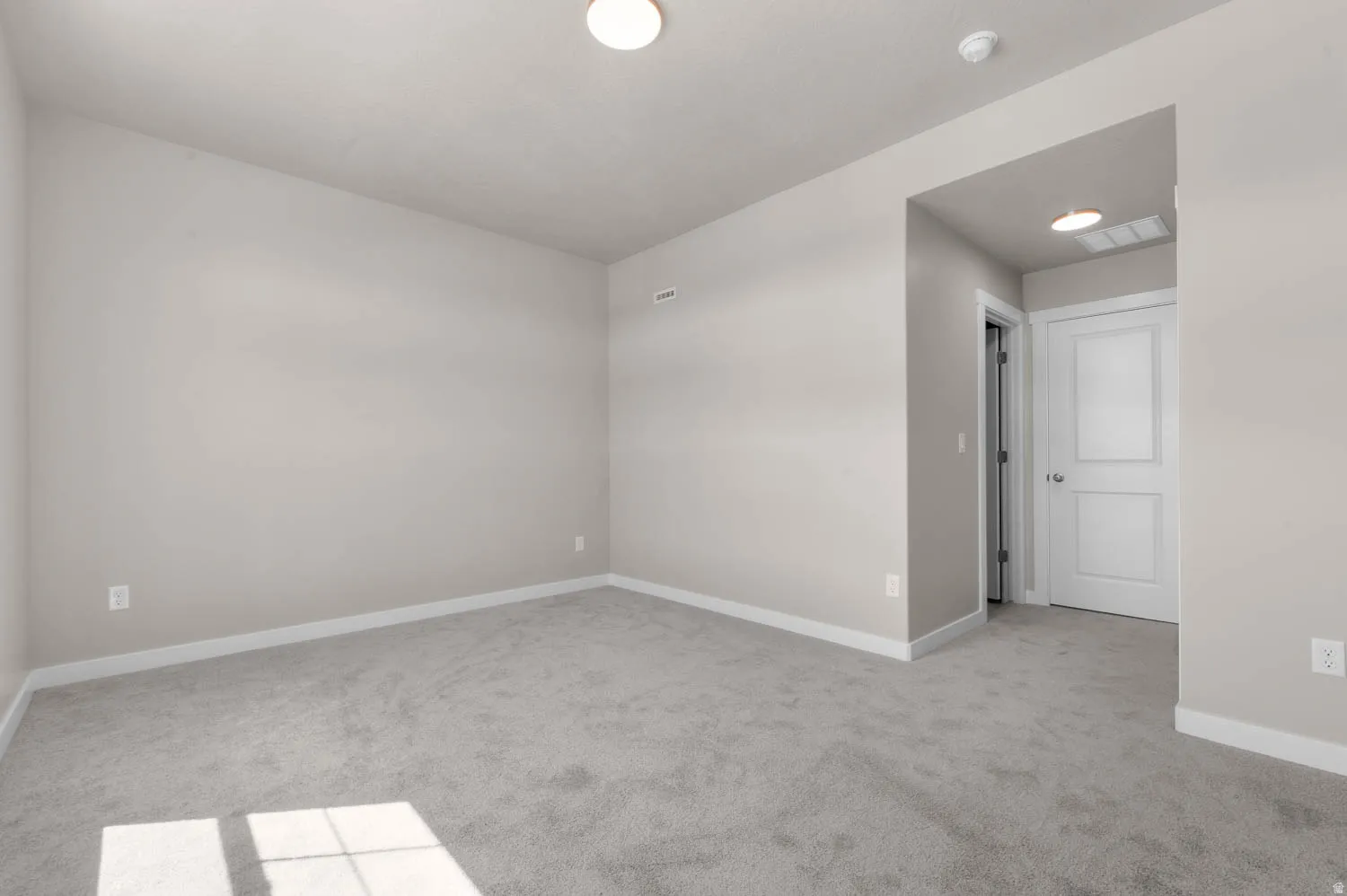 Spare room with light colored carpet and baseboards