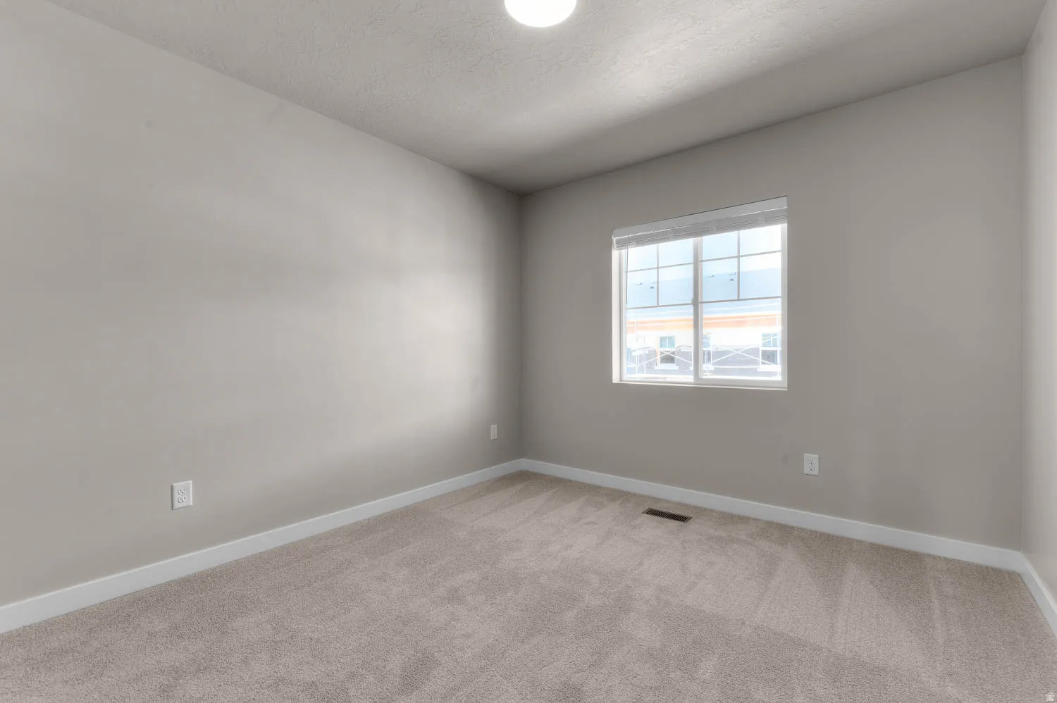 Unfurnished room featuring light colored carpet and a textured ceiling