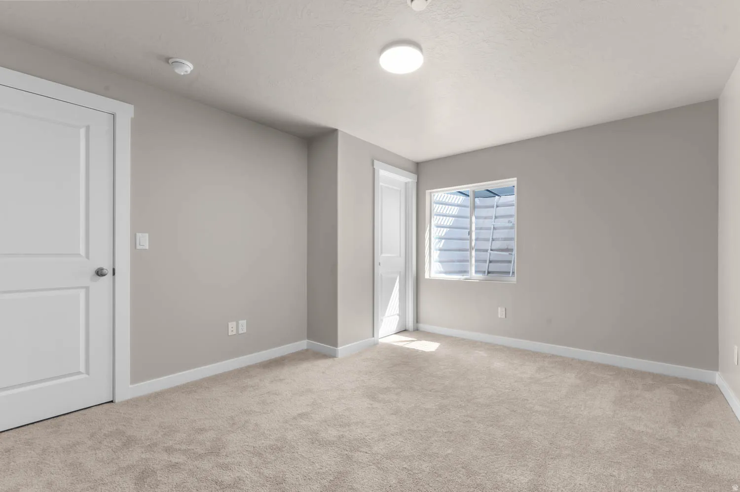 Unfurnished bedroom featuring light colored carpet and baseboards