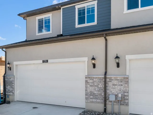View of front of home featuring stucco siding, driveway, an attached garage, and stone siding