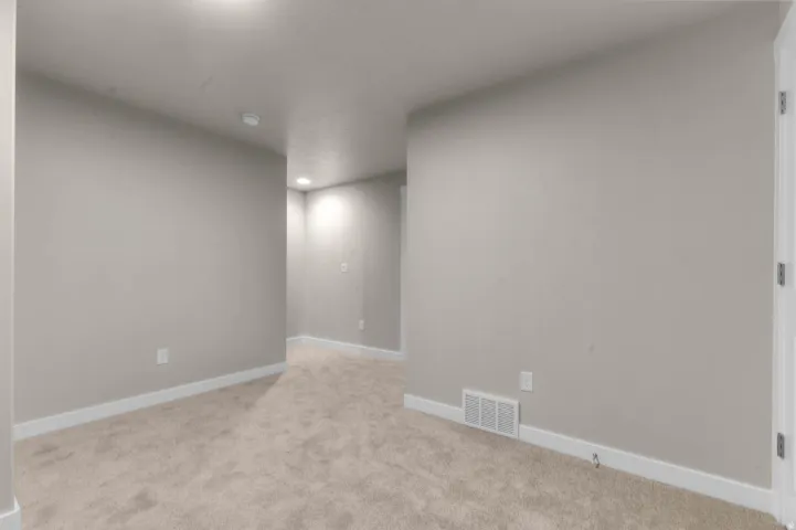 Empty room with light carpet and recessed lighting
